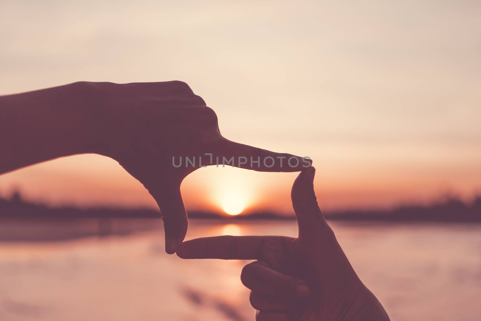 Selective focus of woman hands making frame by finger gesture with sunrise on mountain, Female capture sunrise or sunlight outdoor. Future planning concept.