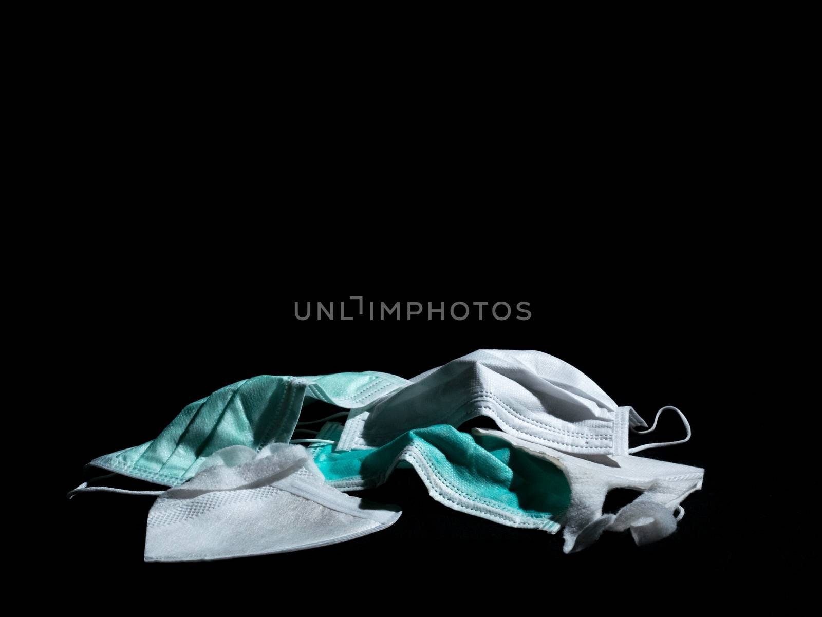 used surgical masks and used PM2.5 masks place on black background with copy space. dark tone. Properly discarded mask concept.