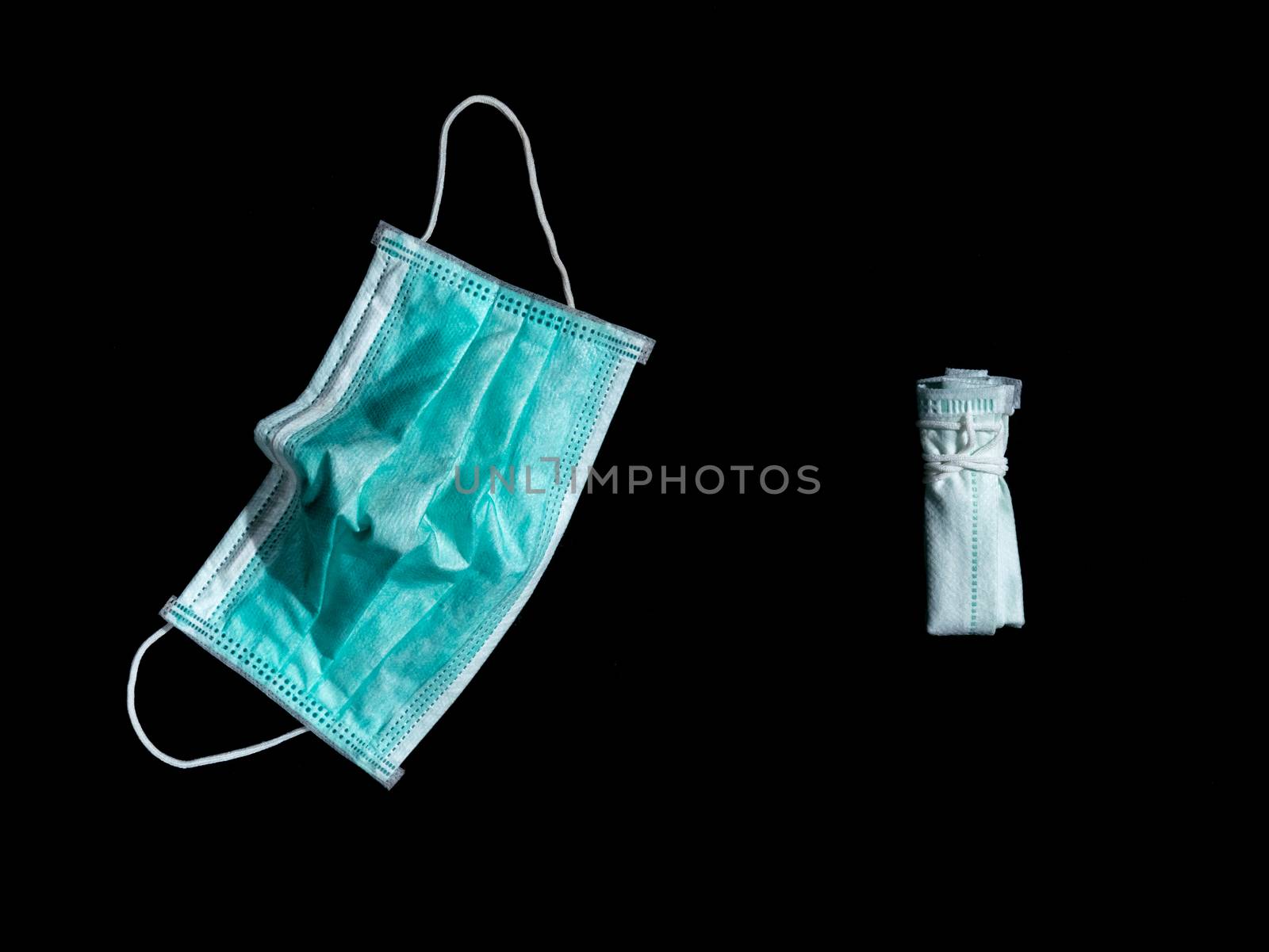 unfolded and folded used surgical mask place on black background. dark tone. Properly discarded mask concept.