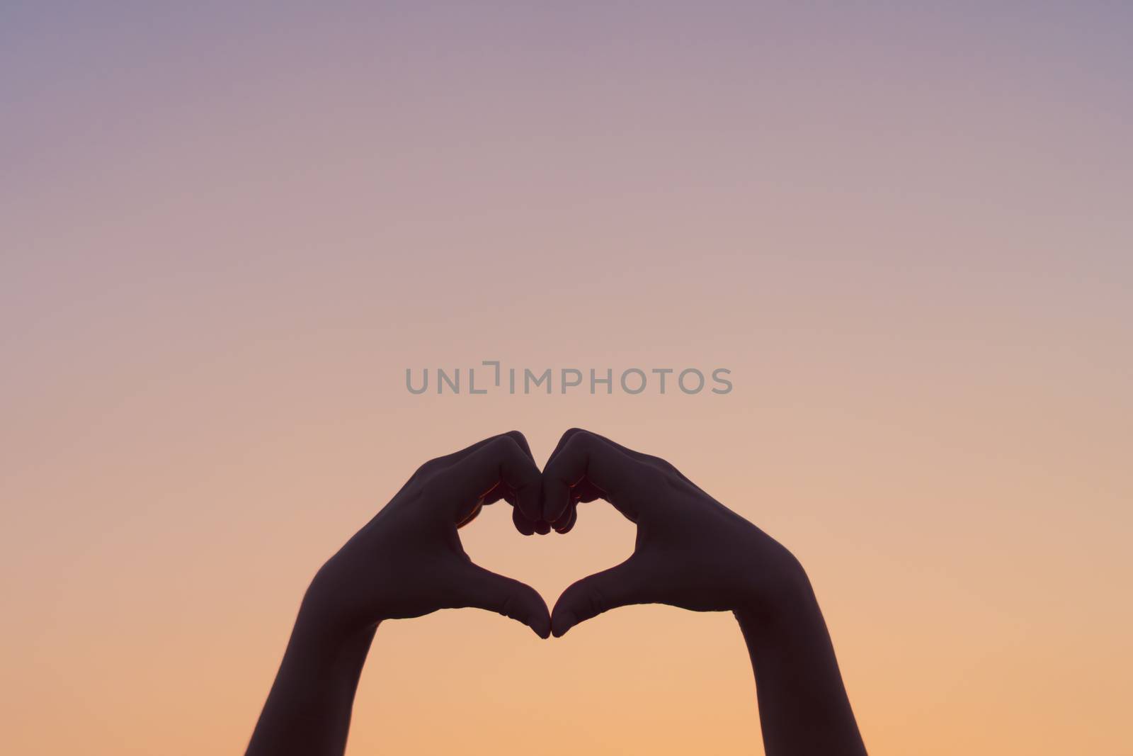 Woman hand do heart shape on blue sky  and bokeh background. by Suwant