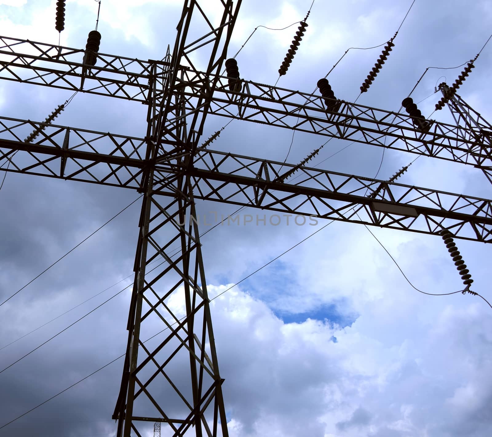 A large electricity pylon with ceramic insulators seen against a dramatic sky

