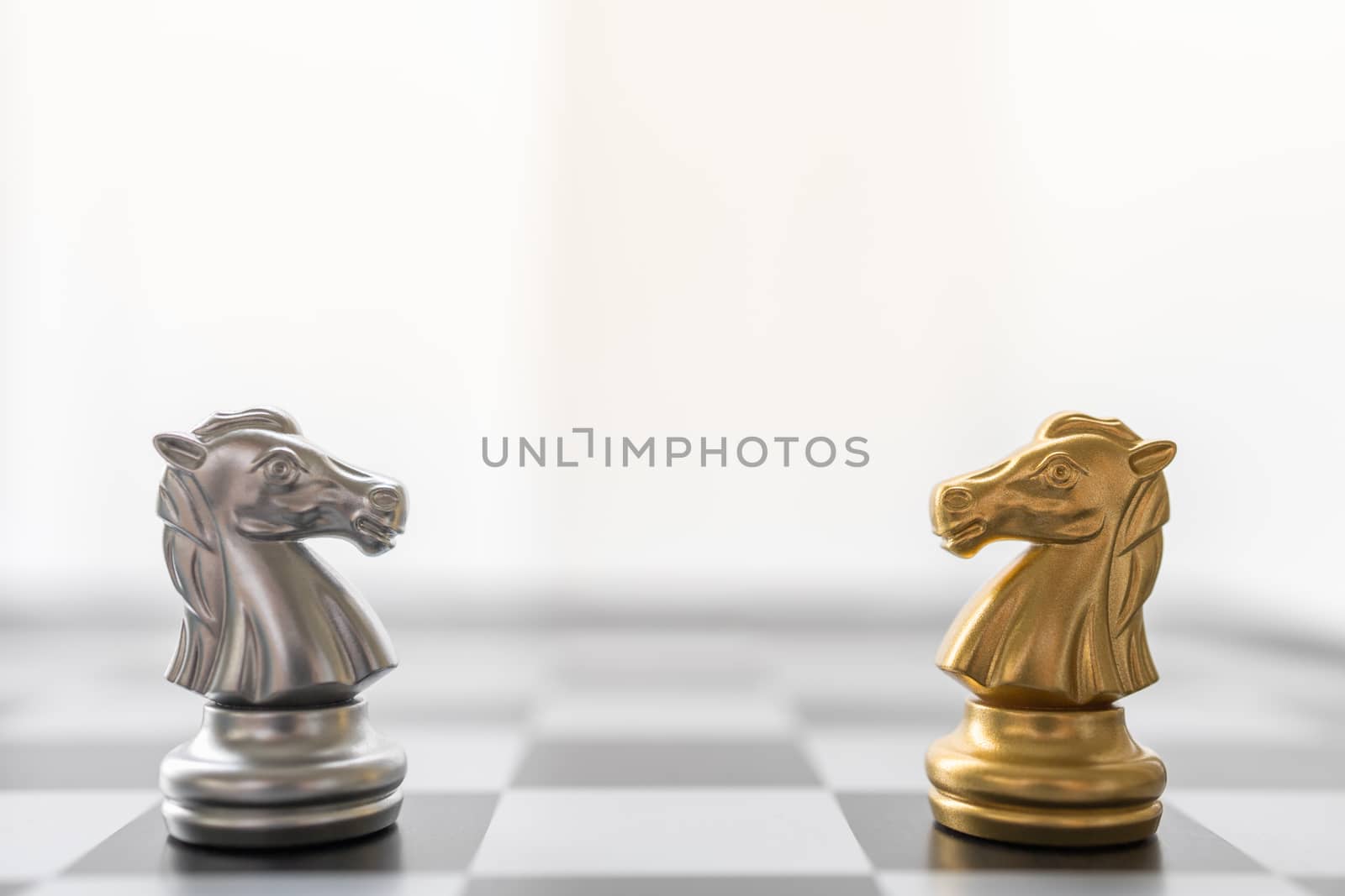 Sport board game, Business and planning concept. Closeup of gold and silver knight chess piece face to face on chessboard with other pieces.