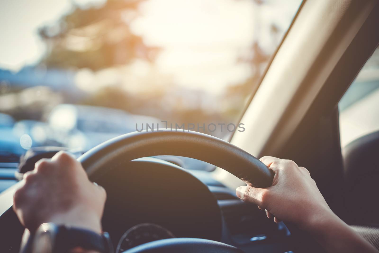 Hand of woman on steering wheel drive a car with sunlight background.