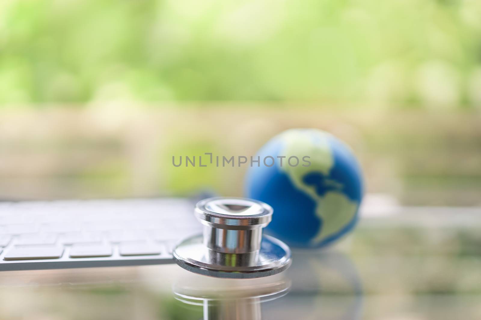 Healthcare, Global, Technology, Corona Virus (COVID-19) Protection Concept. Close up of Stethoscope with computer keyboard and mini world ball with green nature background and copy space.