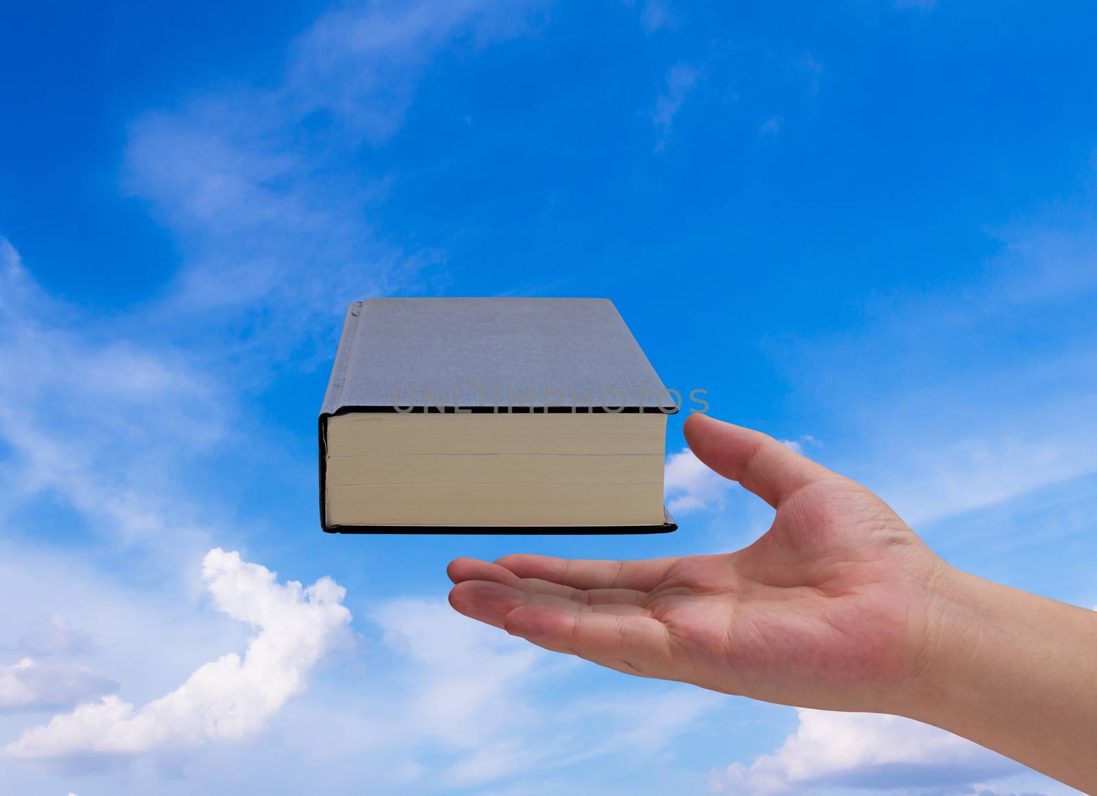 Knowledge management, education concept, hand and book on blue sky background