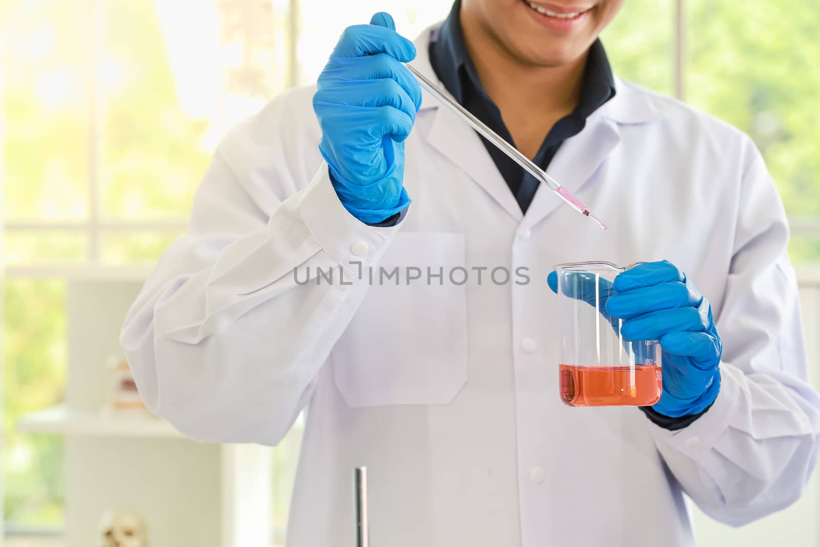 Young doctor scientist using pipette to test and research in wor by mthipsorn