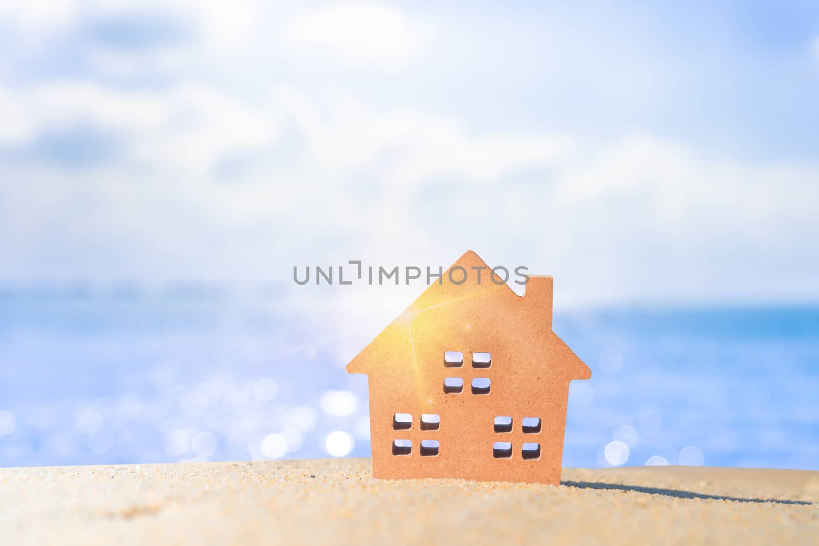 Closed up tiny home models on sand with sunlight and beach background.Investment property concept.