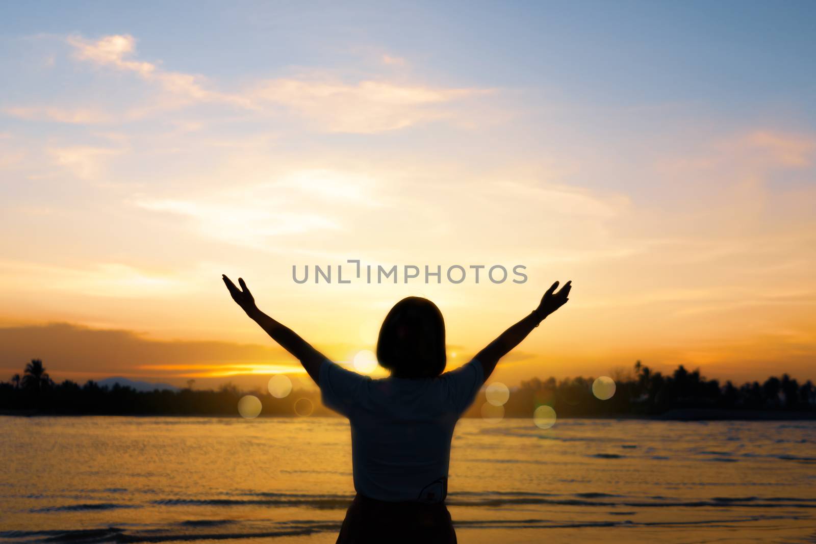 Silhouette woman rise hands up to sky freedom concept with sunset sky and summer beach season background.