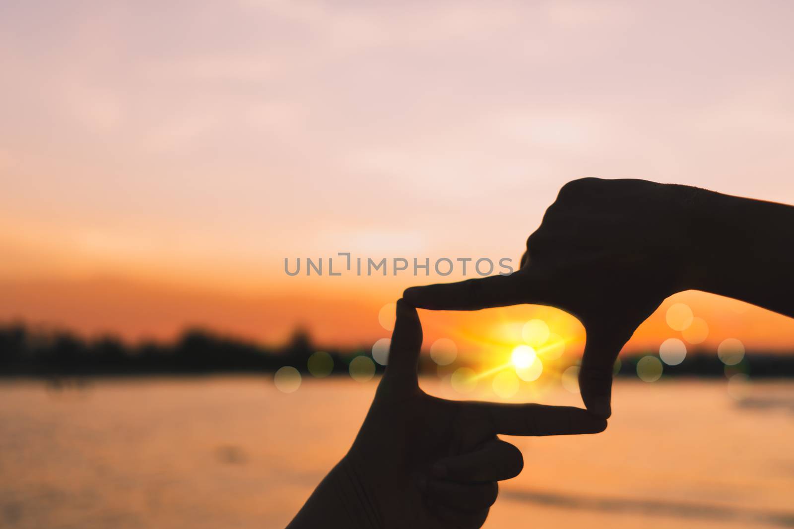 Human hands making a frame sign over sunset sky. by Suwant