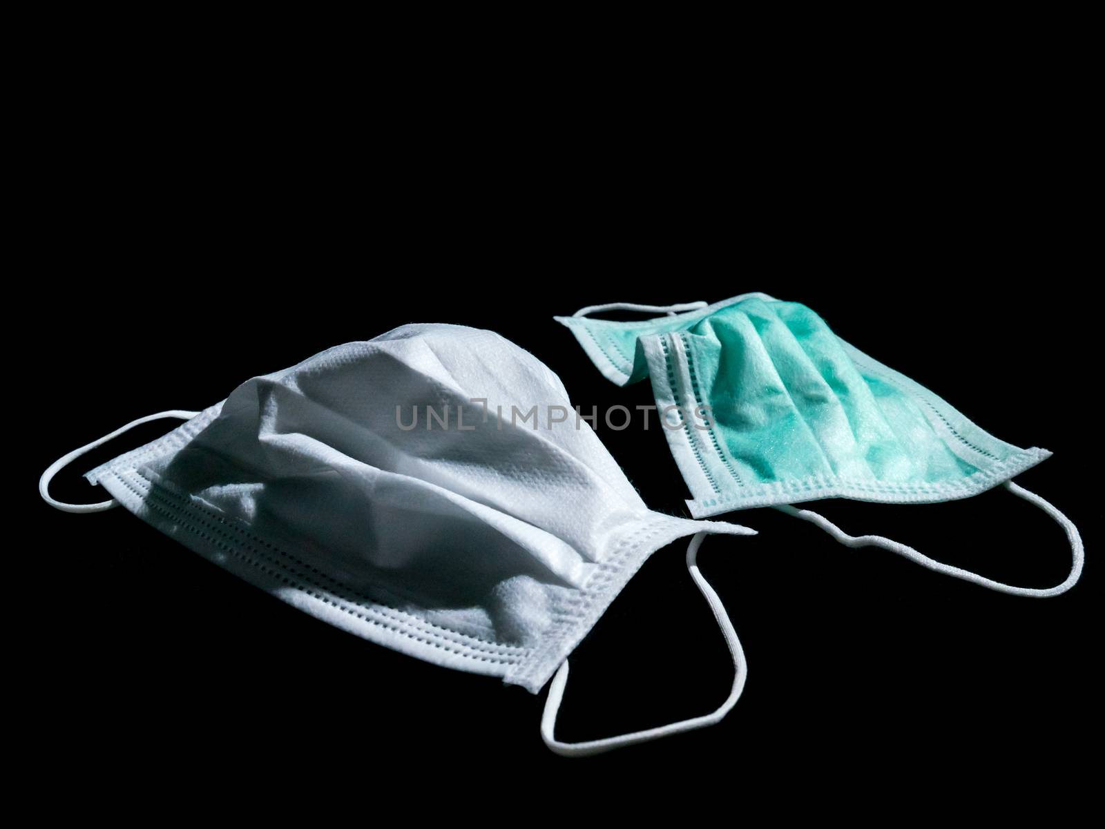 Used white and green surgical mask place on black background, Dark tone.
