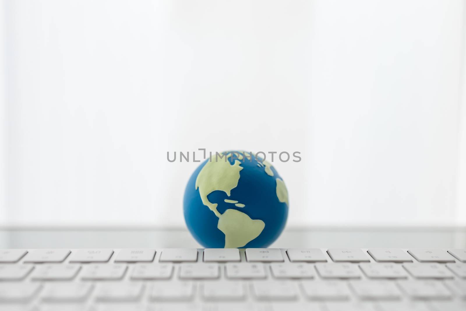Global Business and Technology Concept. Close up of mini world ball with computer keyboard with copy space.