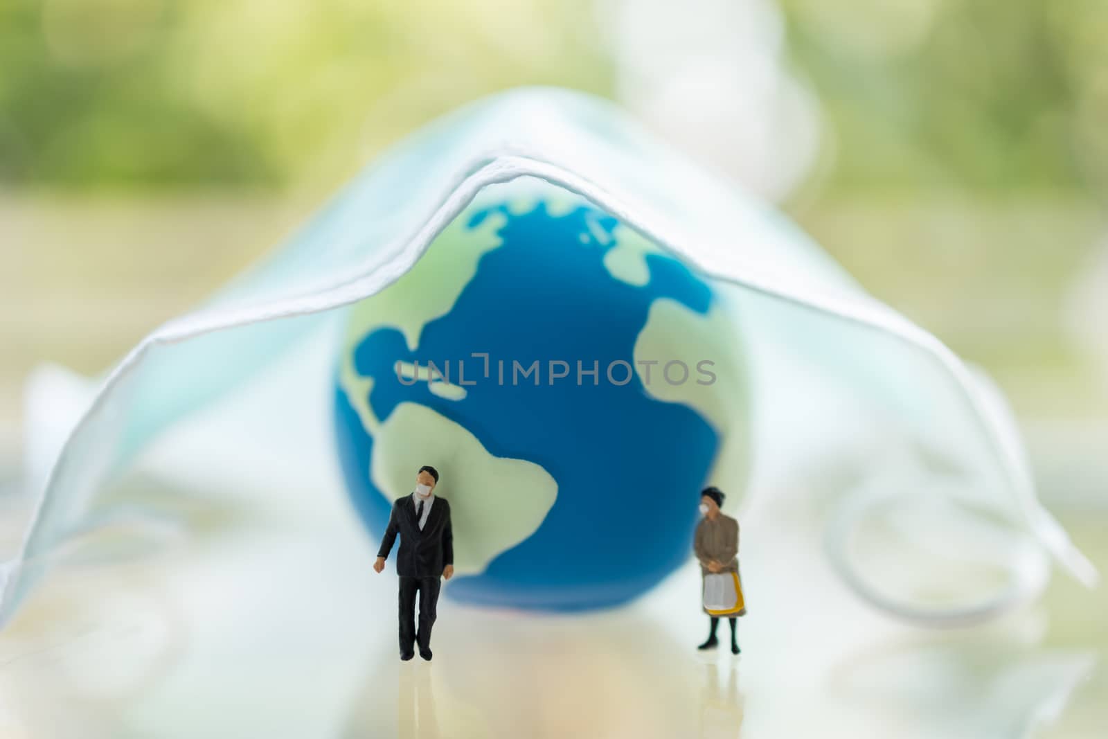 Global Healthcare, Coronavirus, Covid-19 Protection Concept. Businessman and woman miniature figure people wearing face mask standing with mini world ball and surgical face mask.
