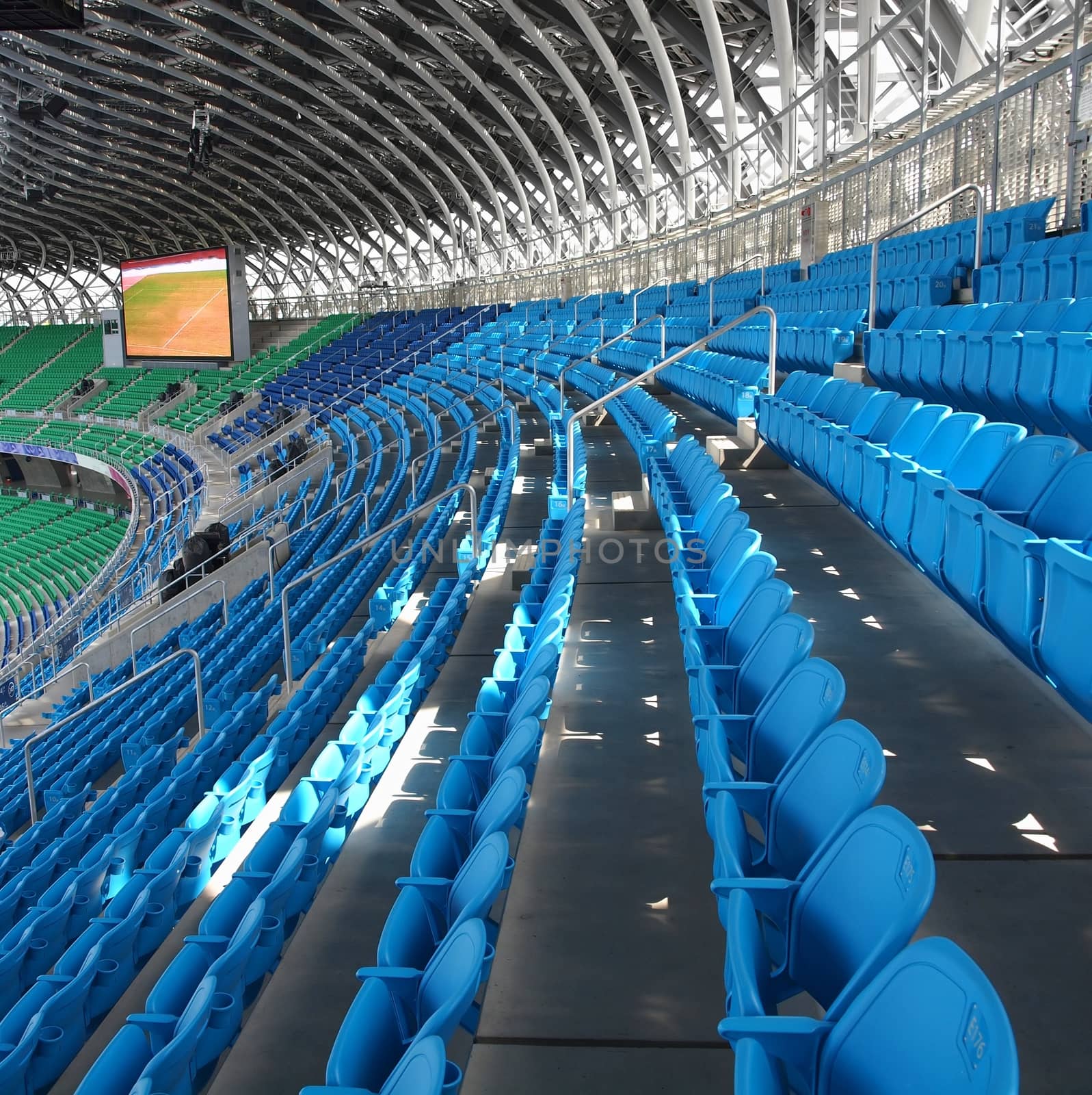 A large stadium with rows of blue folding plastic chairs