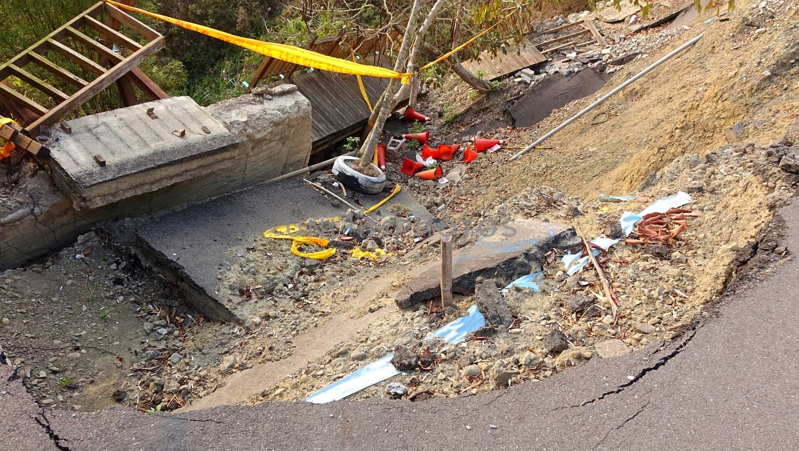 A road and built structures are damaged by a landslide
