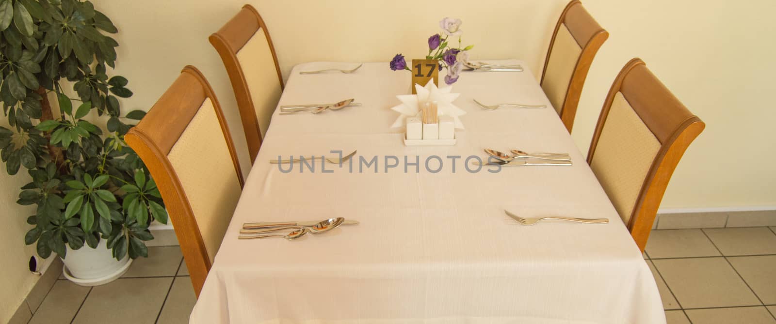 Festive table with tablecloth and Cutlery in the hotel restaurant waiting for guests, side view.