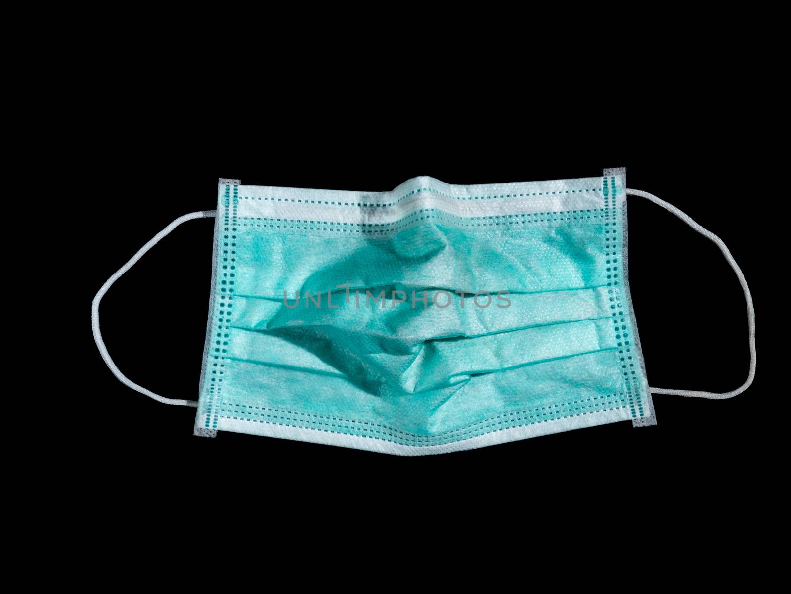 Used surgical mask place on black background, discarded mask concept. Dark tone.
