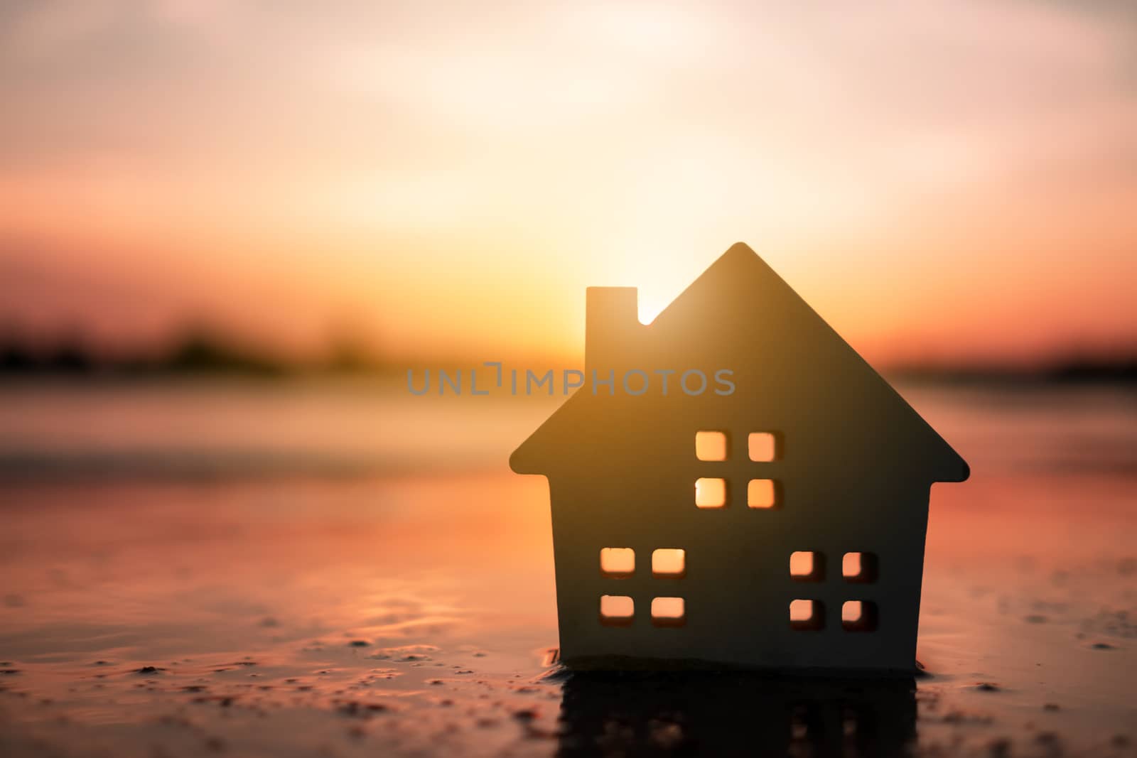 Model of a little house on sand with nature beach background. Dream life concept.