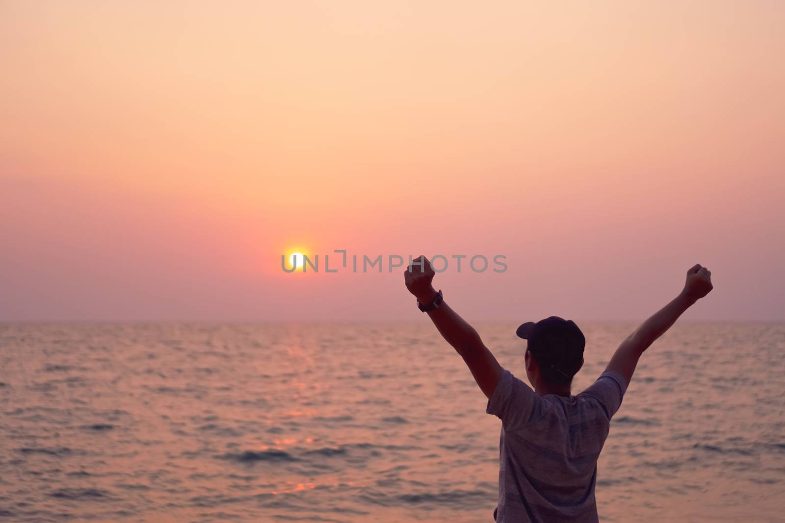 Man rise hands up to sky freedom concept with sunset sky and summer beach background.