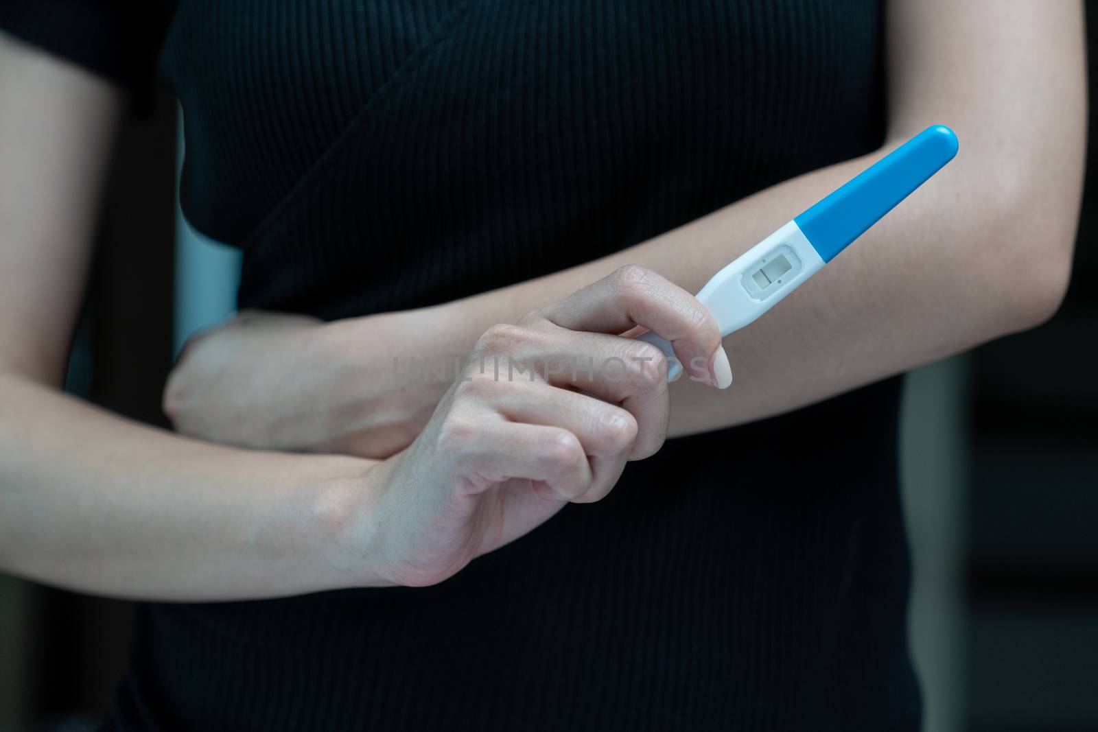 Female hand holding negative pregnancy test, with not pregnant results.