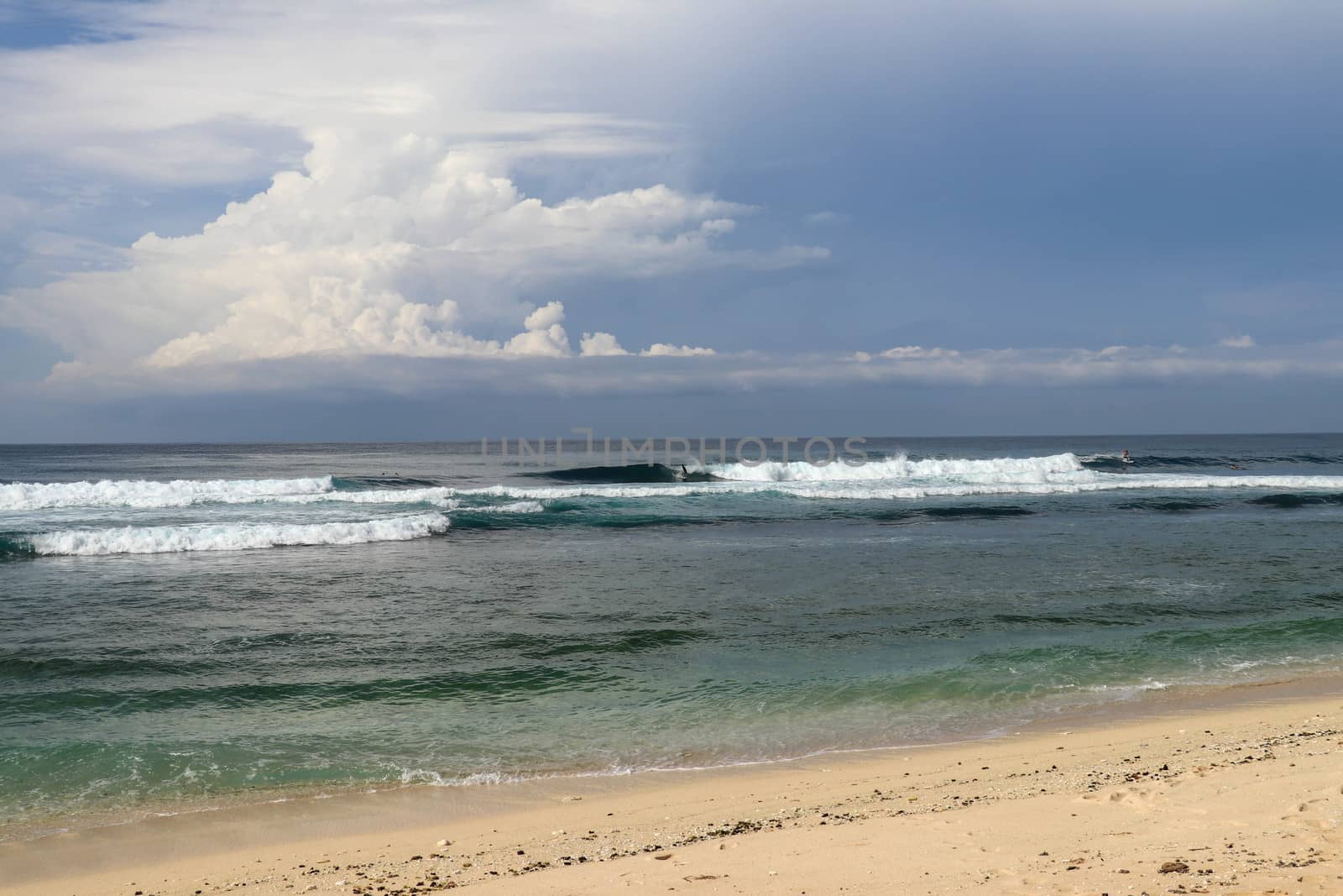 Virgin beach with fine yellow sand on Bali island. Lonely tropical paradise with Nyang Nyang beach. Azure blue sky, sunny day. Wild waves are approaching the shore in rows. Sea foam in rolling waves.