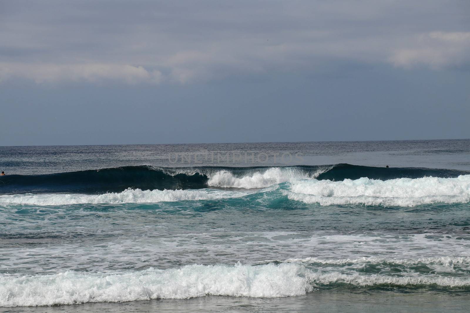 Big breaking wave with glowing green water and big white spray and foam filling the frame. Image taken in Bali. Big large surfing wave during big swell. A Perfect big breaking Ocean barrel wave.