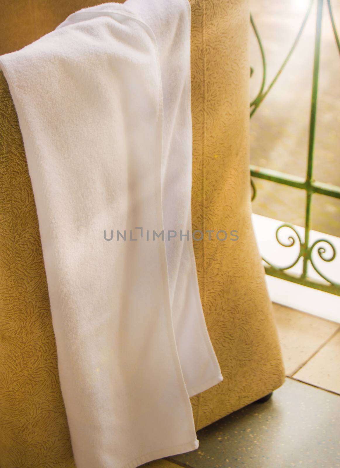 White Terry towel hanging on a chair, towel drying on the balcony, outdoor terrace against the background of sunlight, vertical shot by claire_lucia