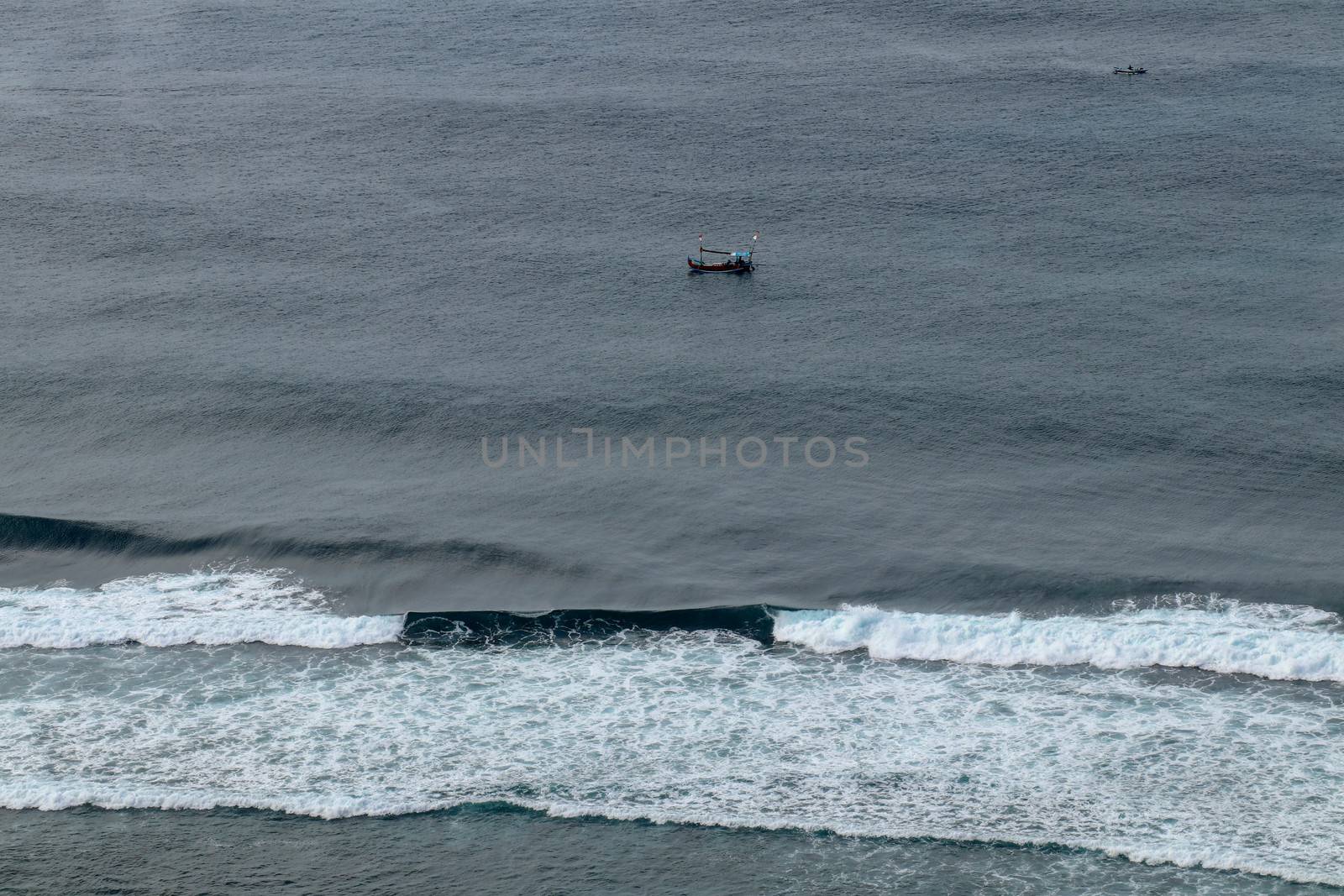 Aerial view of Nyang Nyang beach on Bali in Indonesia. A popular spot of surfers with big waves in the Indian Ocean. Fishing boats of Balinese fishermen on the sea surface. Waves break off the coast.