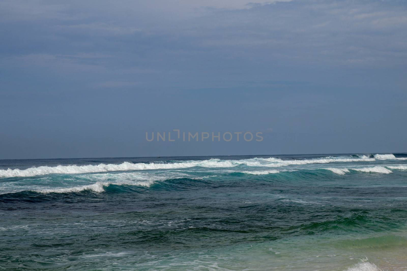 Big breaking wave with glowing green water and big white spray and foam filling the frame. Image taken in Bali. Big large surfing wave during big swell. A Perfect big breaking Ocean barrel wave.