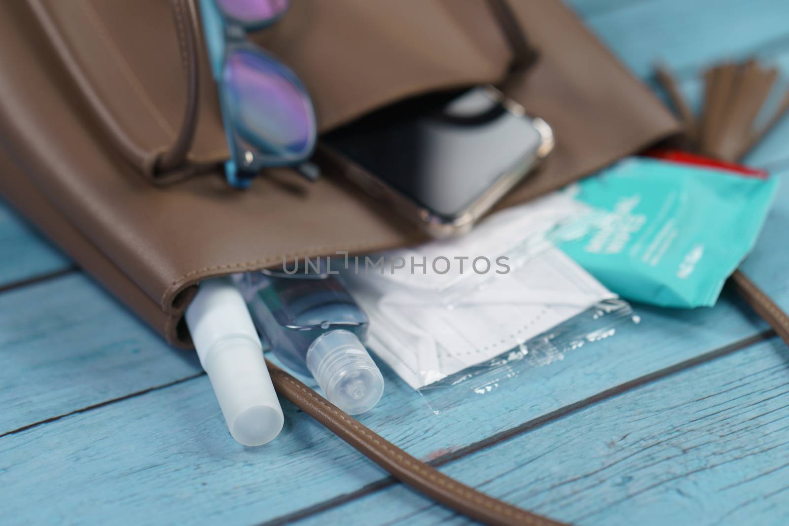 Hand bag with 2020 must have items smart phone, protective face mask, glasses and sanitizer gel corona virus or Covid-19 protection.