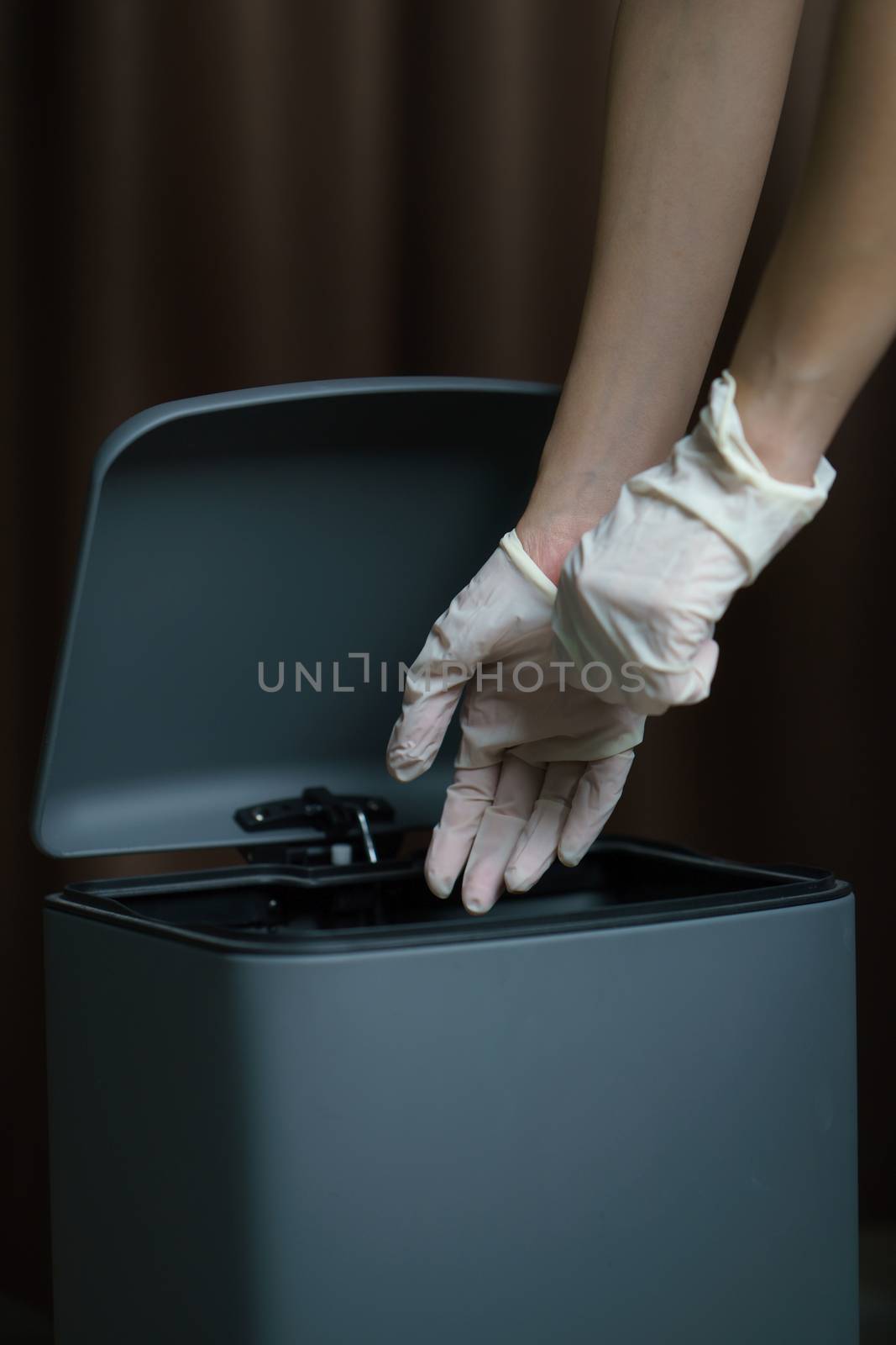 Hand putting used dirty surgical glove to a garbage bin. Mask protect dust and corona virus in trash.