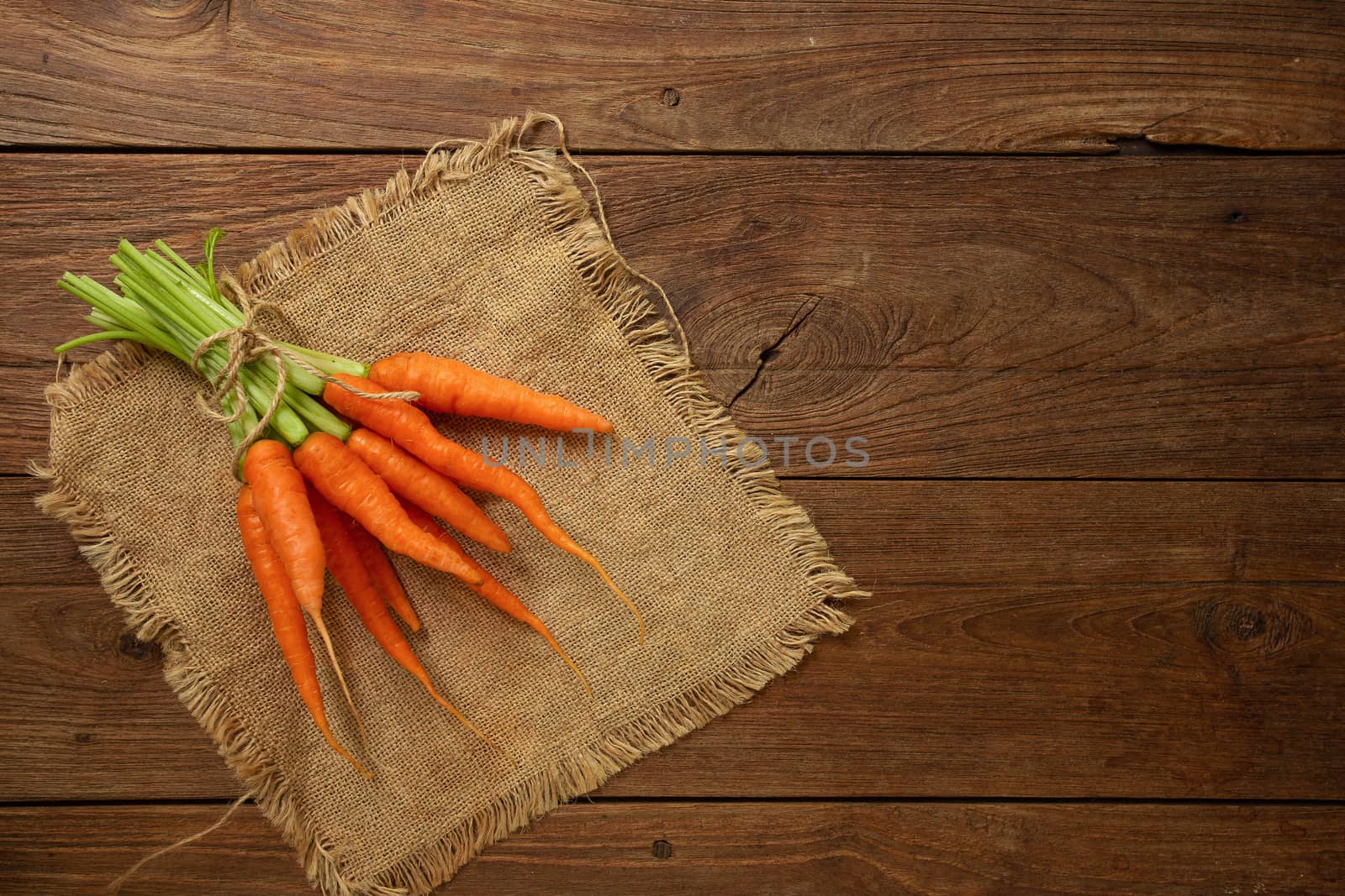 Fresh baby carrots on wooden cutting board and wooden background.