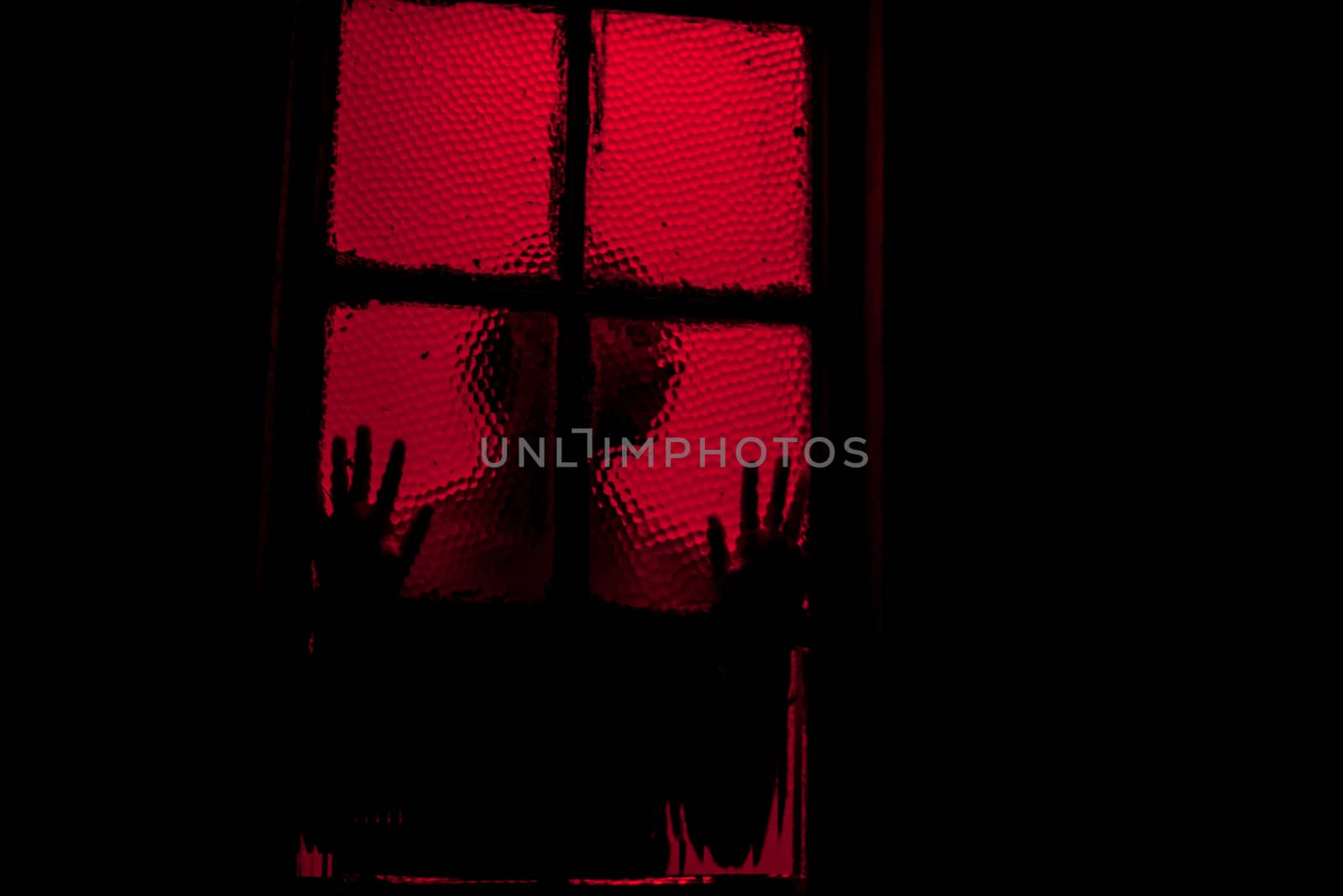 Person leaning against window in room filled with red light