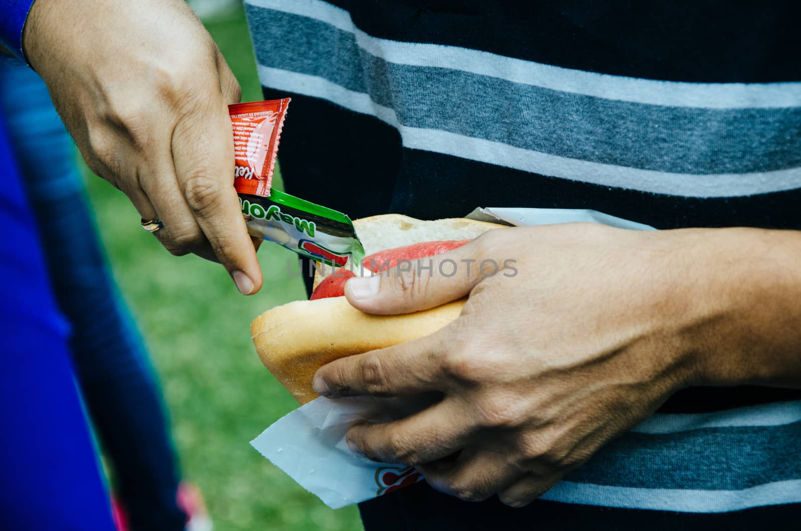 Bread with chorizo in one hand, serving with mayonnaise