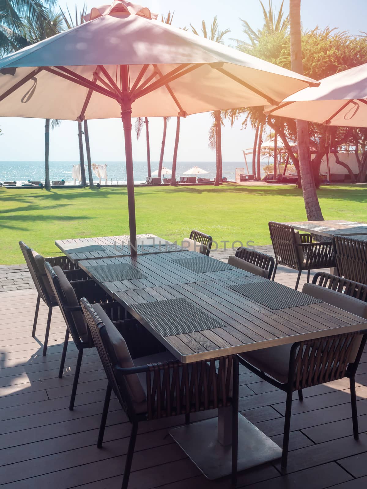 Wooden dining table and chairs with beach umbrella with sea view by tete_escape