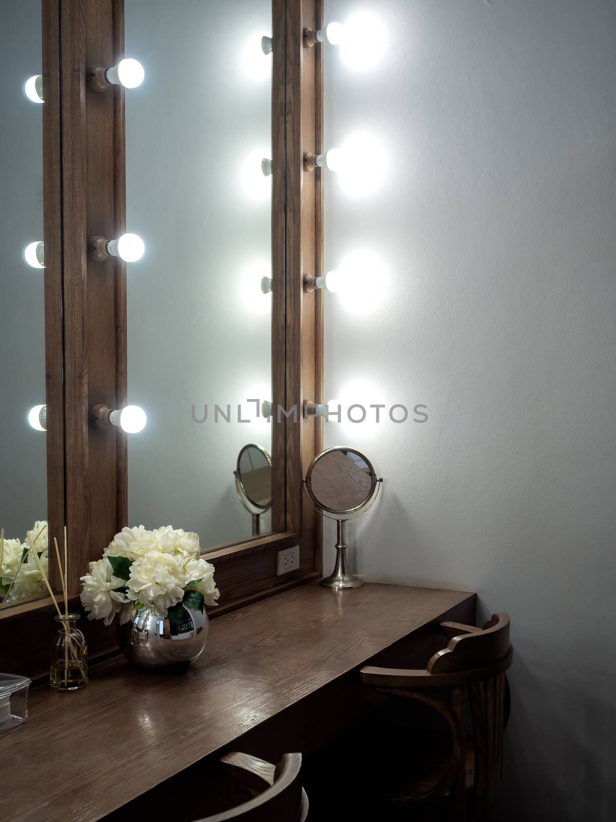 Makeup room classic and vintage style decoration with long wooden table, wooden chairs, mirrors with light bulbs and modern flower pot, vertical style.