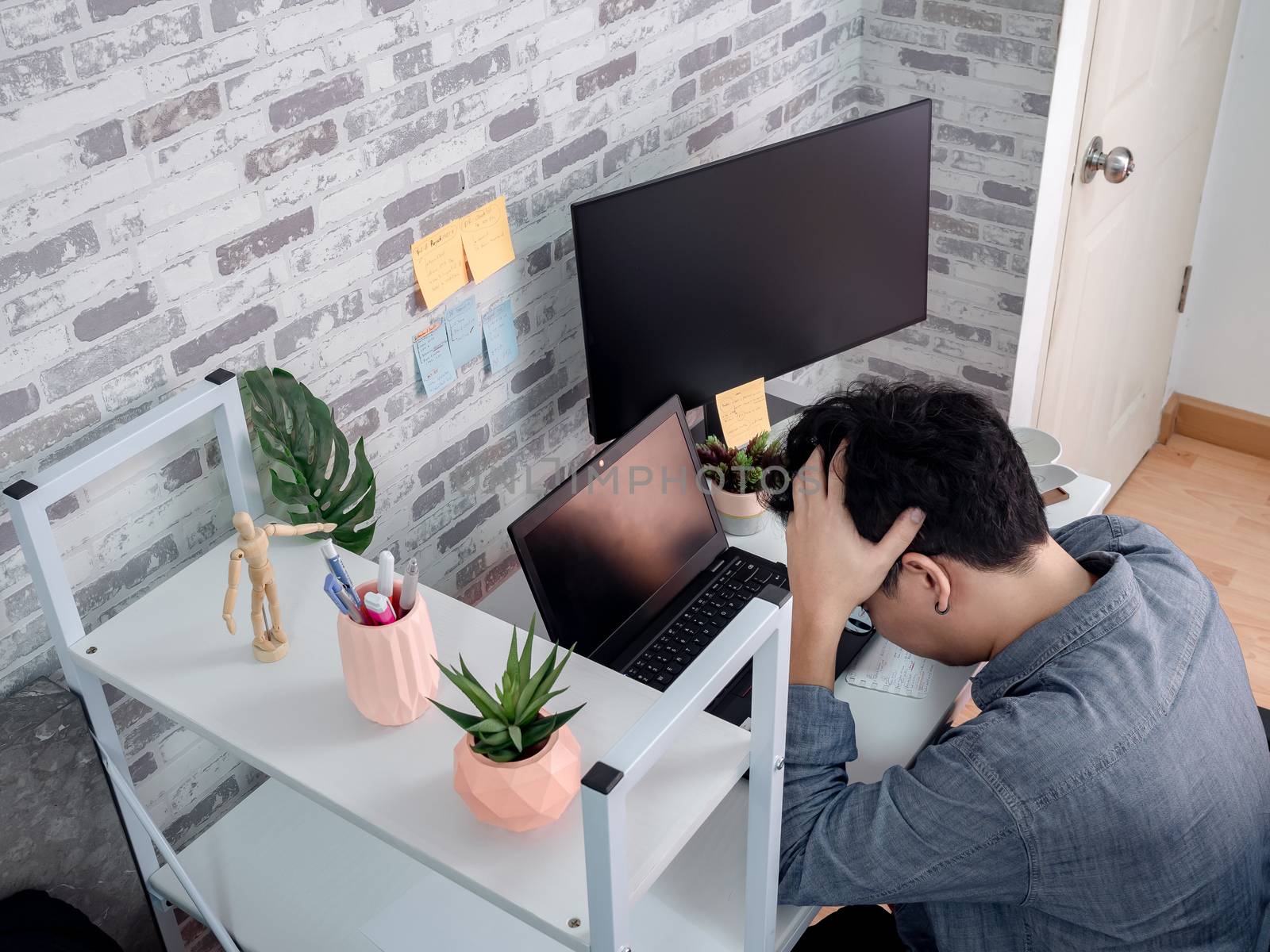 Asian serious man put hand on his head with feeling fail and working with laptop computer in his room, condominium. Work at home and business online concept.