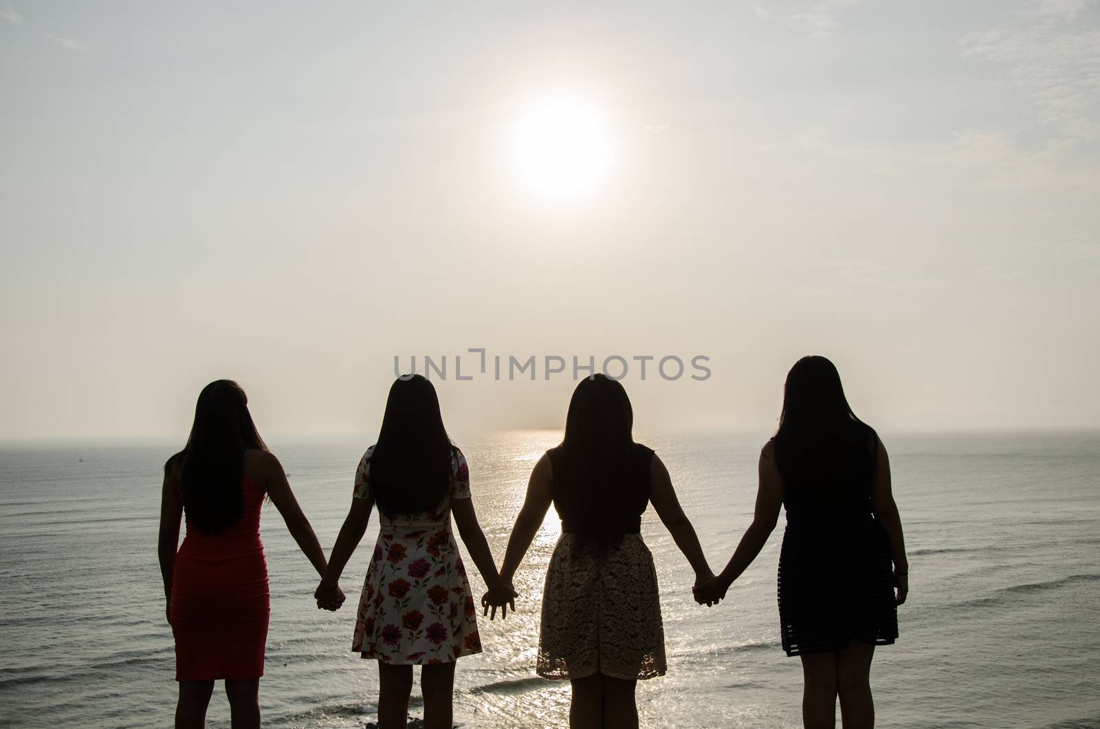 Girls in front of the sunset holding hands