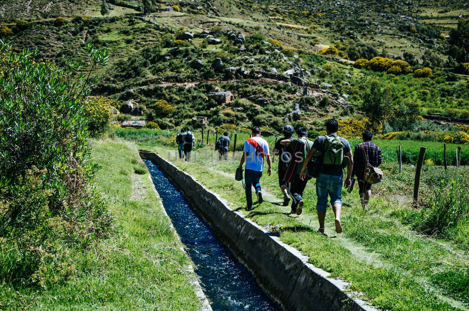 Travelers walking through a path with a stream