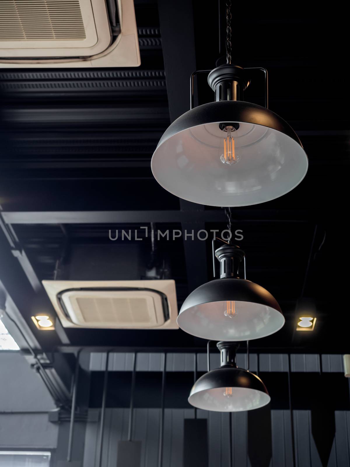Three black round modern ceiling lights and cassette type air conditioner inside the cafe loft style, vertical style.