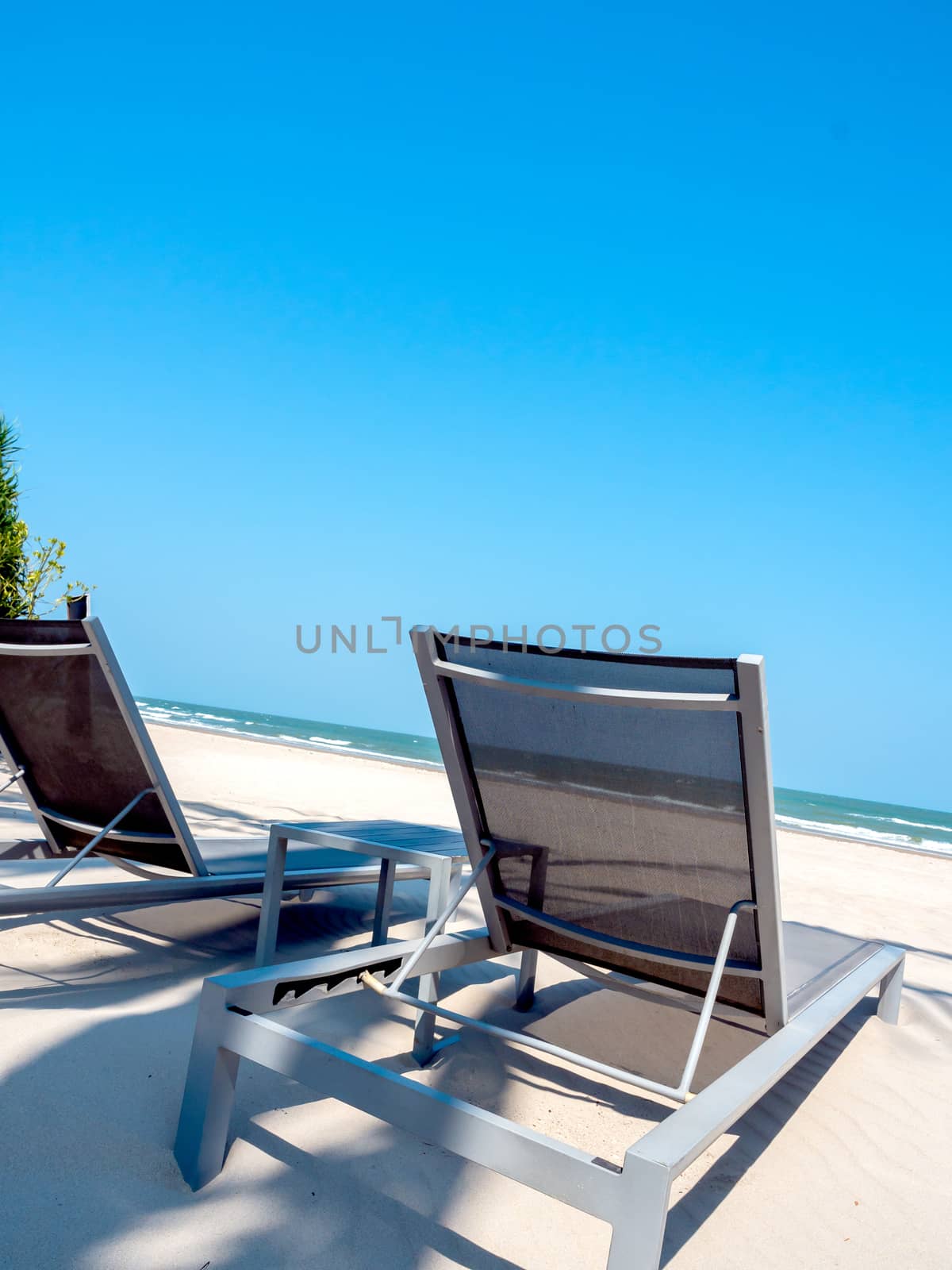 Empty wooden sunbed on sand beach on blue sky background.