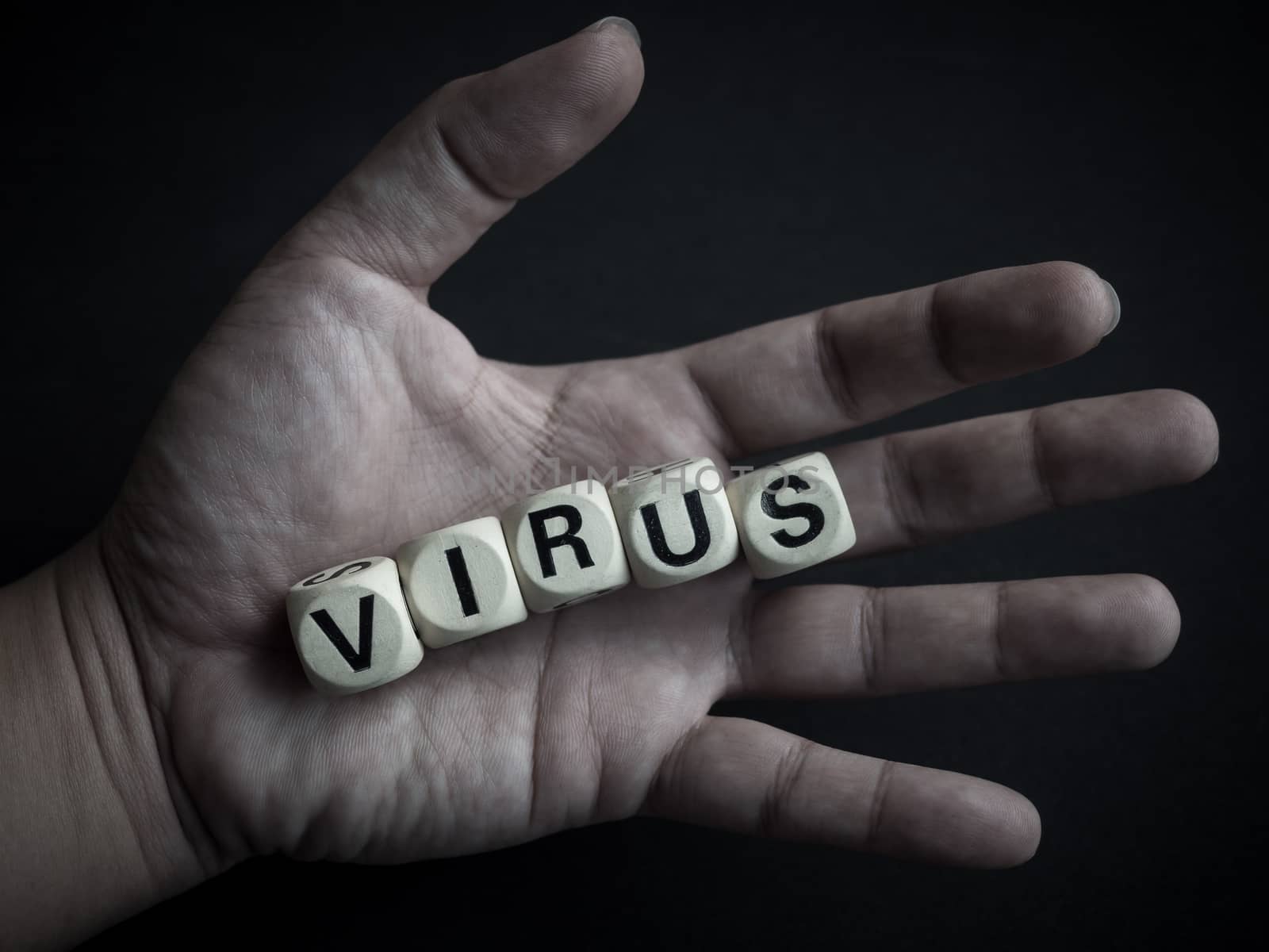 Coronavirus or Covid-19 concept. Wooden cubes text "VIRUS" in hand on dark background.