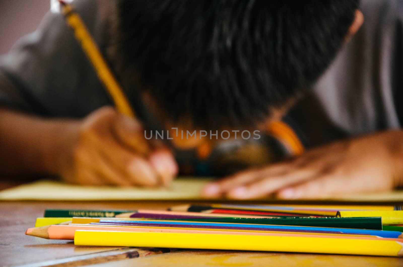 Child painting with colored pencil on a paper
