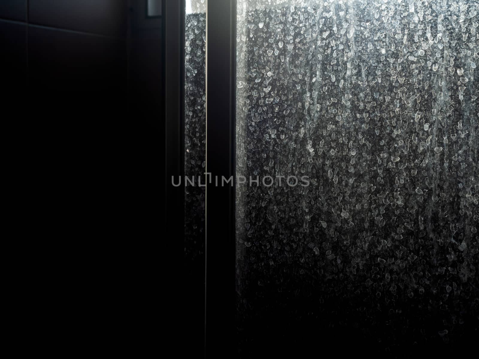 Dusty and dirty glass door. Water stain on sliding door in bathroom, dark background.