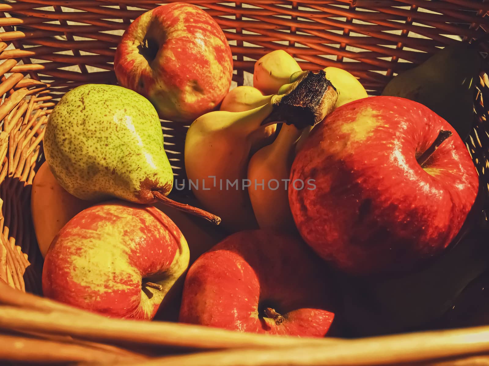 Organic apples, pears and bananas on rustic in a wicker basket by Anneleven