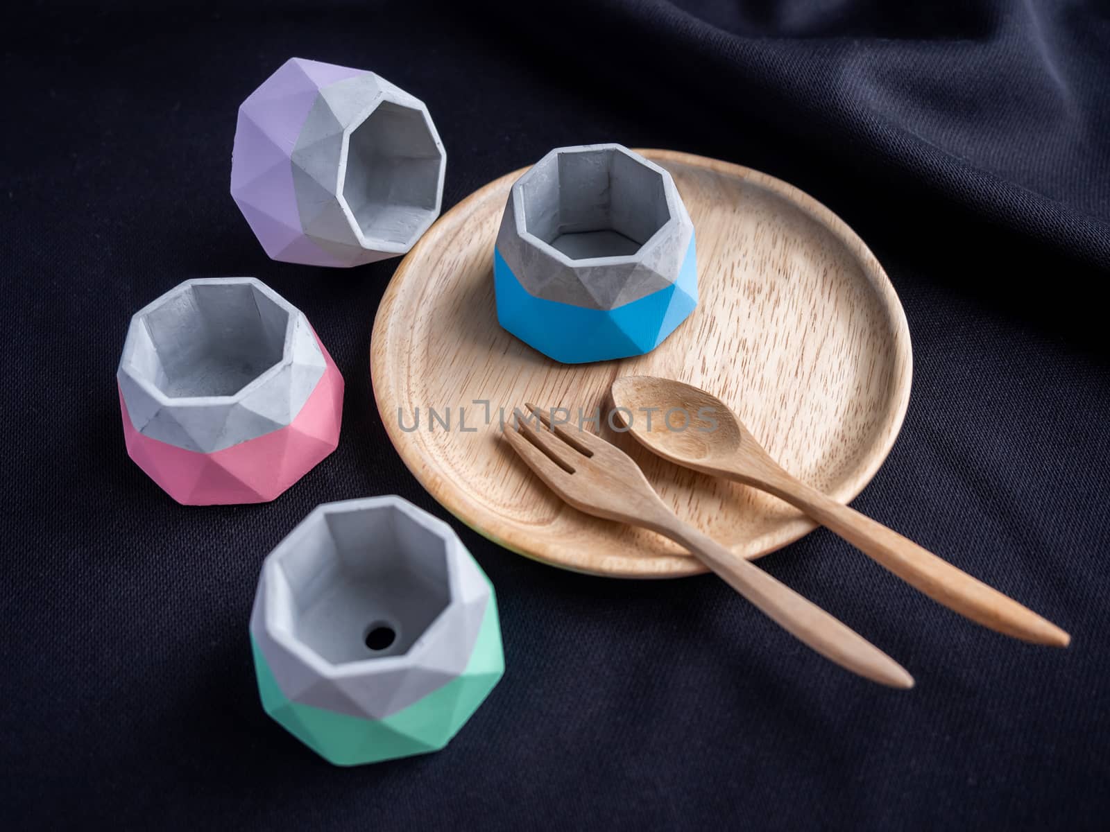 Cactus pot. Concrete pot. Beautiful empty small modern geometric concrete planters with painted on wooden plate on black fabric background.
