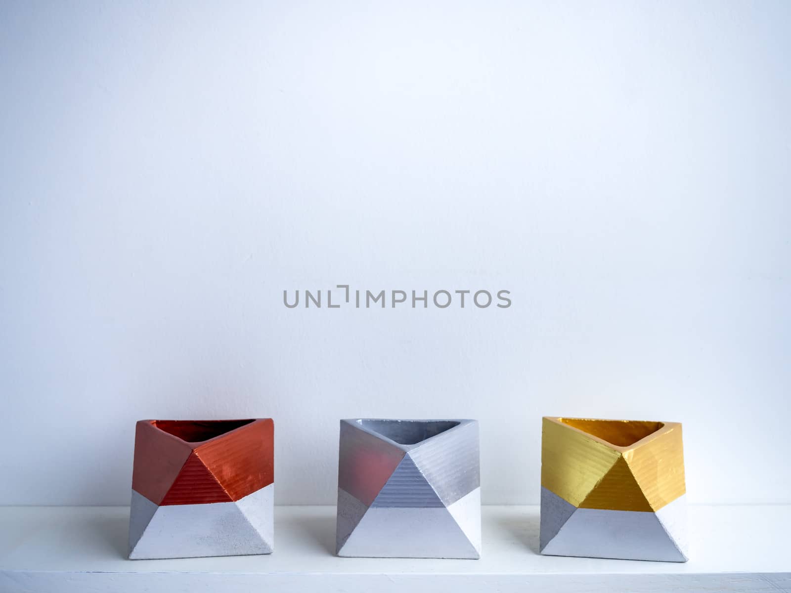 Cactus pot. Concrete pot. Gold, silver and copper painted geometric concrete planters on white shelf isolated on white background.