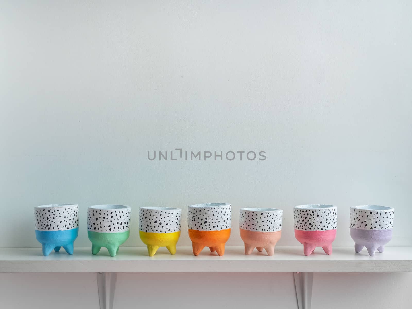 Cactus pot. Concrete pot. Empty colorful cute small concrete planters on white wooden shelf isolated on white background with copy space.