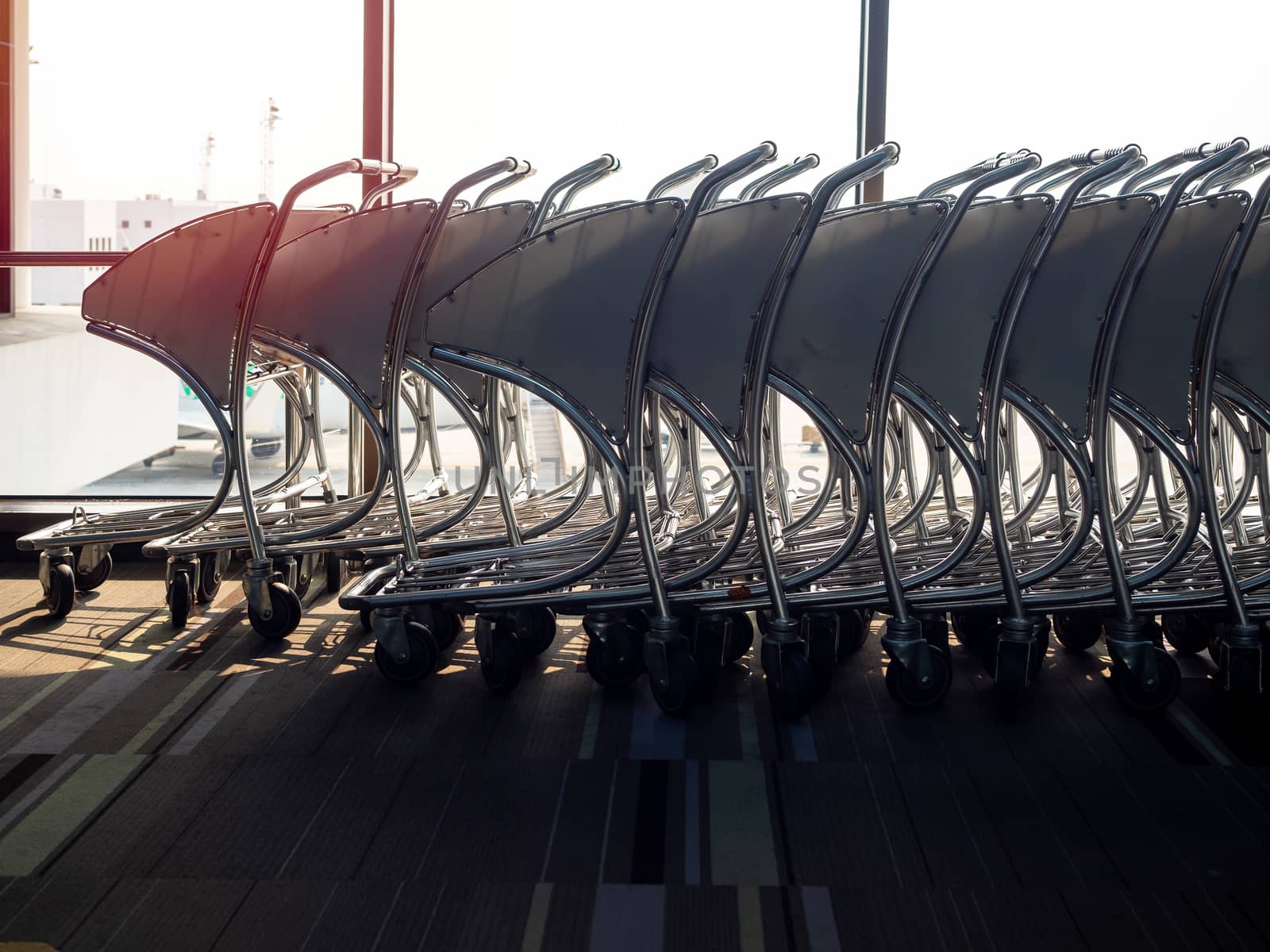 Airport luggage cart in airport near the glass window.