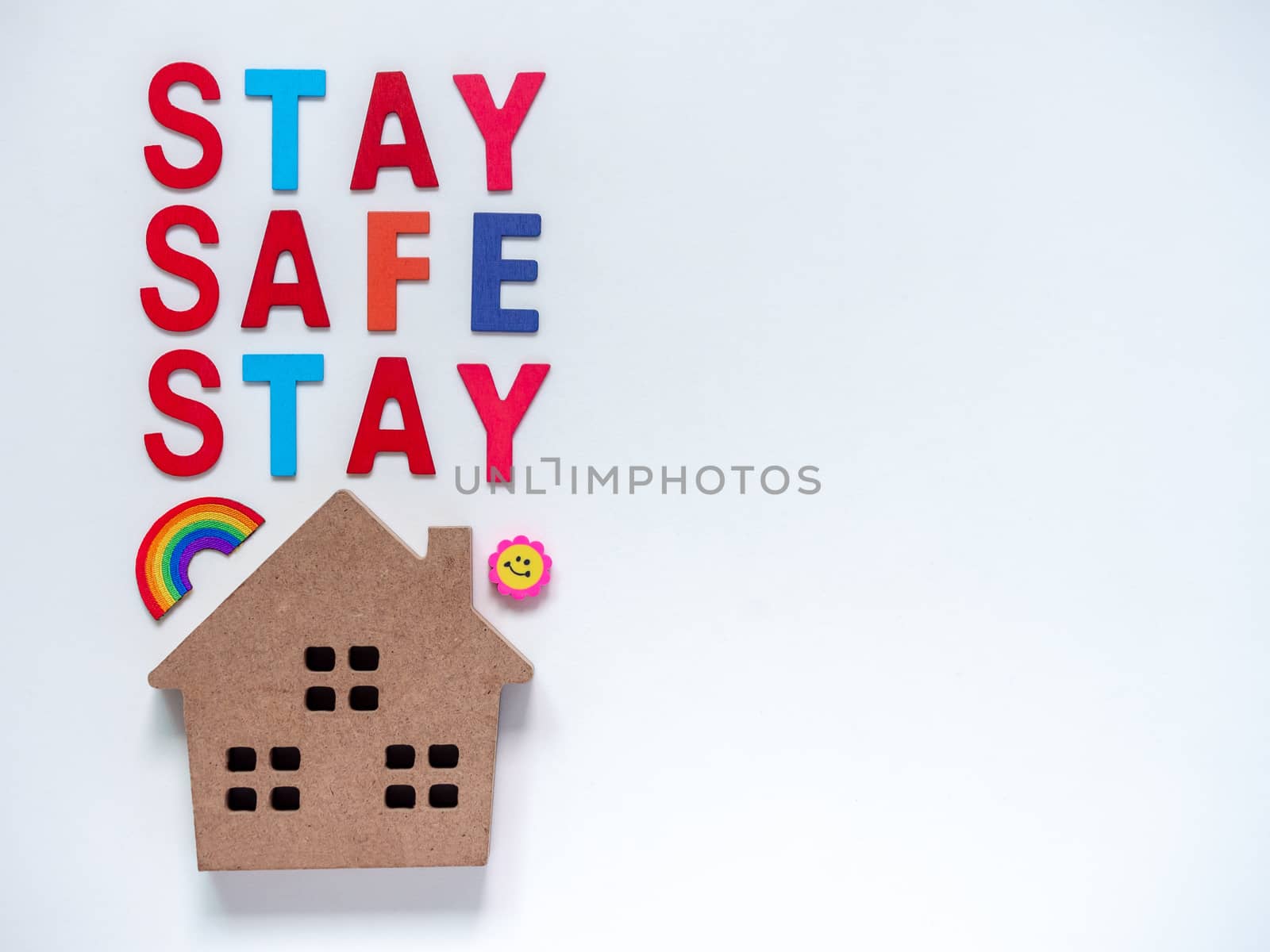Stay safe concept. Colorful word "Stay Safe" with wooden home isolated on white background with copy space, stay at home, social media campaign for covid-19 or coronavirus pandemic prevention.