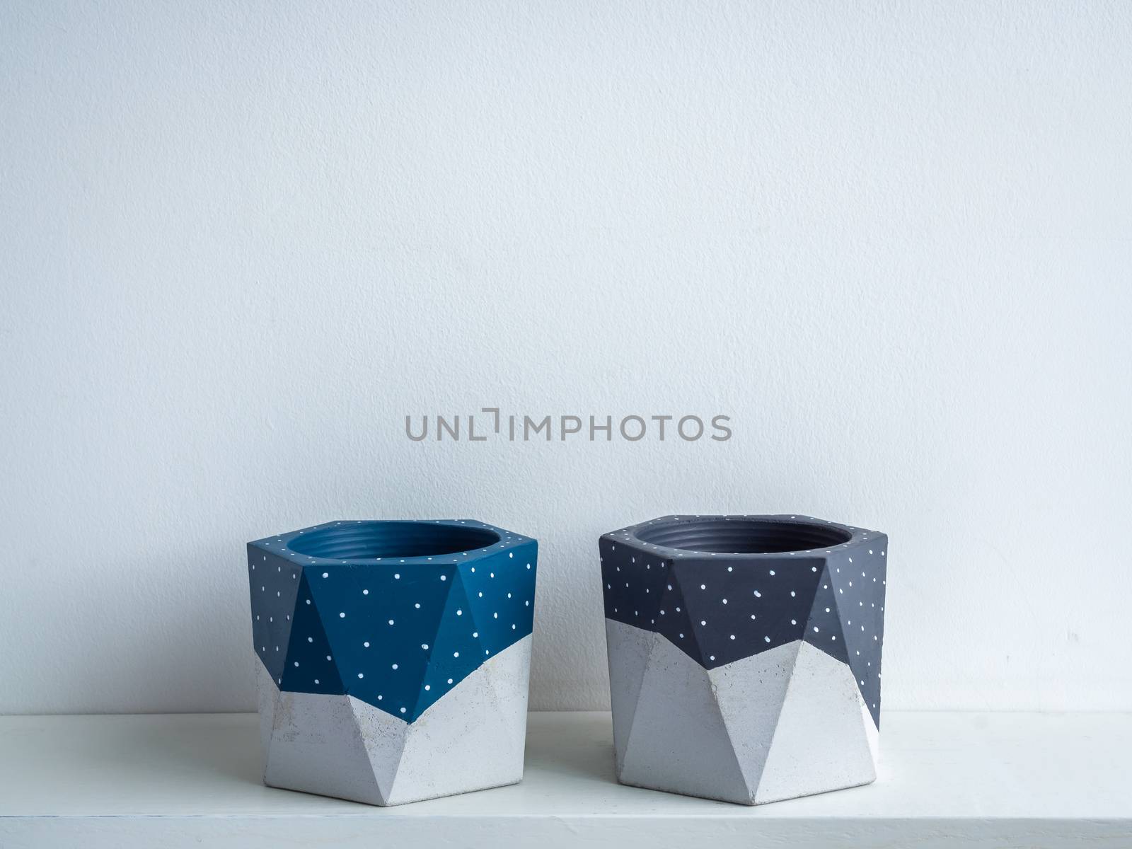 Cactus pot. Concrete pot. Empty blue and grey painted modern geometric concrete planters on white wooden shelf isolated on white background.
